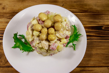 Potato salad with marinated mushrooms, sausage, onion and mayonnaise on wooden table