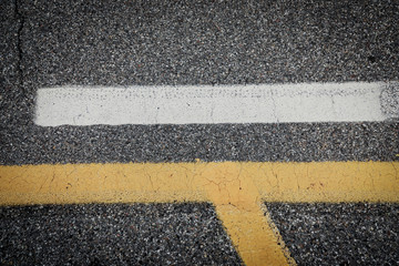 yellow and white lines on the road, traffic signs on asphalt, cracked street with lines