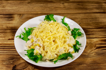 Festive salad with chicken breast, sweet corn, canned pineapple, cheese and mayonnaise on wooden...