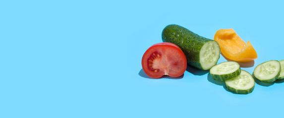 Ripe green cucumber, yellow pepper and red tomato on blue background. Healthy eating and dieting concept. Copy space. Free space for your text