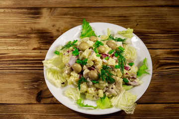 Potato salad with marinated mushrooms, eggs, red onion and mayonnaise on wooden table