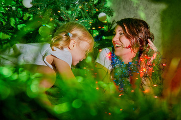 Nice mother and her cute daughter near Christmas tree in the room