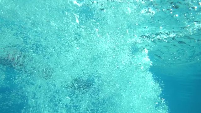 Underwater view of girl jumping in the pool, slow motion