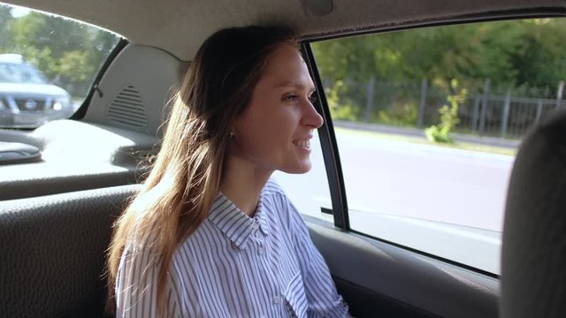 Beautiful young woman rides in taxi in backseat enjoying the ride. 4k.