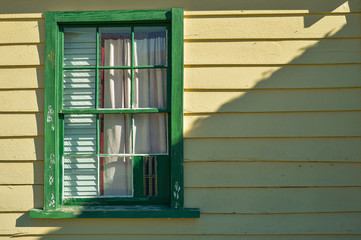 Obraz premium Beautiful antique green window and white curtain with sunshade on white wall house background.
