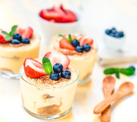 dessert tiramisu in glasses, decorated with blueberries, strawberrys and mint, the concept of delicious life
