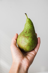 Female hand holding a green pear.