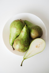 Green pears in white plate on white background.