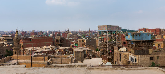Shabby buildings with satellite dishes on rooftops located against blue sky in ancient city of...