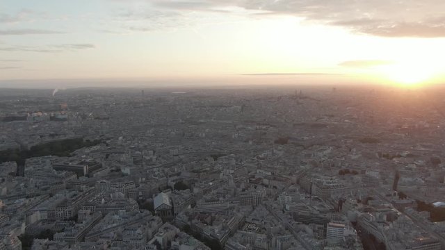 aerial drone shot of the endless cityscape of Paris, France while sunrise with montmartre in the background grrowing due to urbanization