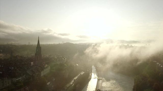 The old town of Bern, Switzerland in an aerial shot. The cityscape is partly covered by clouds.