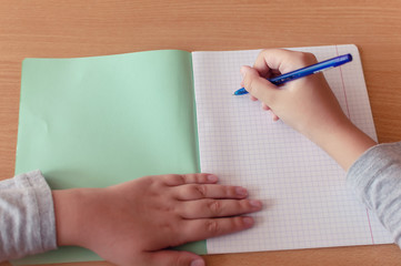 hand of a teenage girl writes with a ballpoint pen in a terad during a lesson at school