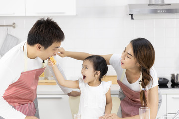 Happy Asian family make a cooking. Father, Mother and Daughter are eating breakfast in the kitchen at home. Bread with jam. Healthy food concept