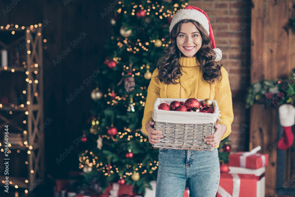 Sticker Photo of charming cute lady holding box with christmas toys balls while wearing red hat jeans denim yellow pullover