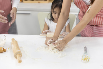 Asian Women thresh flour with daughter for making bakery in the kitchen in home. family cooking food Concept.