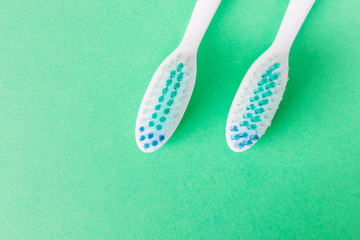 Two toothbrushes close-up on a green background. The concept of oral hygiene, dentistry, dental health care, the choice of hygiene products for the oral cavity. Copy space, fat lay.
