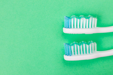 Two toothbrushes close-up on a green background. The concept of oral hygiene, dentistry, dental health care, the choice of hygiene products for the oral cavity. Copy space, fat lay.