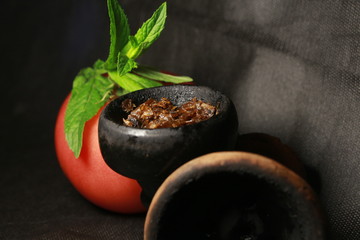 bowl with tobacco for hookah. fruits and berries on a black background. smoke hookah