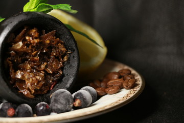 bowl with tobacco for hookah. fruits on a black background