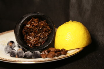 bowl with tobacco for hookah. berries on a black background