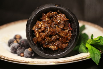 bowl with tobacco for hookah. fruits on a black background