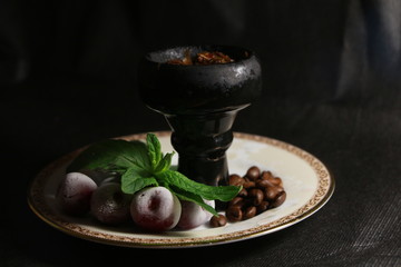 bowl with tobacco for hookah. fruits on a black background. smoking hookah