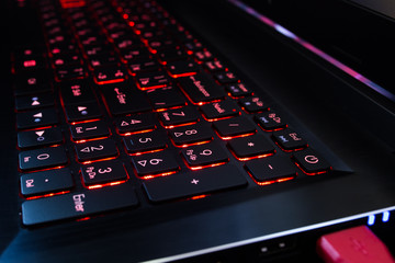 Red backlit laptop keyboard. Close-up.