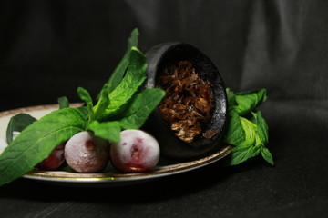 bowl with tobacco for hookah. fruits and berries on a black background. smoke hookah