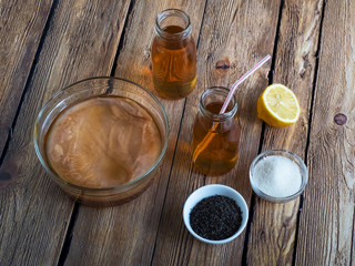 Kombucha by fermenting tea with symbiotic culture of bacteria and yeast on wooden table.