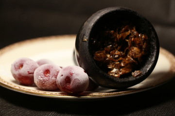 bowl with tobacco for hookah. fruits and berries on a black background. smoke hookah