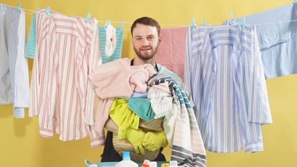 Happy man with stack of dirty clothes in hands looking at camera, expressing happy emotion