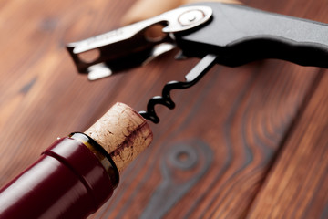 Corkscrew and bottle of wine on the board - Image