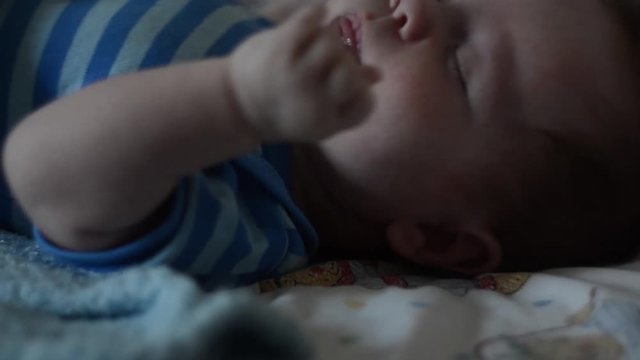 baby sleeping in crib. 3 months old baby boy (European appearance) sleeping under a blue towel in own crib