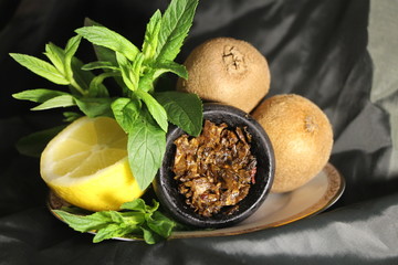 bowl with tobacco for hookah. fruits and berries on a black background. smoke hookah