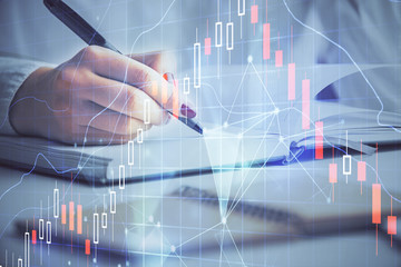 Multi exposure of woman's hands making notes with forex graph hologram. Concept stock market analysis.