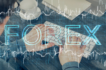 Double exposure of graph with man typing on computer in office on background. Concept of hard work.