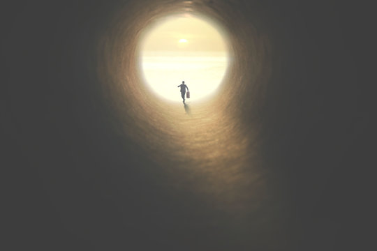 man with suitcase running to the exit of a tunnel illuminated of the sun