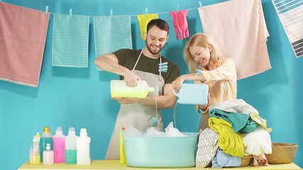 Cheerful young woman and man rejoicing at good detergents. Family advertising washing soap. Wet clean clothes hanging on clothespin.