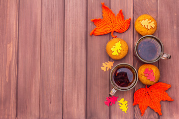 Hot autumn drink. Black tea with cupcakes, colorful leaves