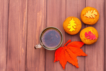 Hot autumn drink. Black tea with cupcakes, colorful leaves
