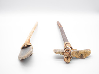 Replicas of the primal stone tools with wooden handles and leather strapping isolated on white background. Primitive stone axe and dagger or spear: weapons of the prehistoric peoples. Selected focus.