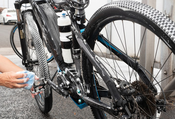 A senior  woman with grey hair in activity. works hard washing his bicycle and taking care of the...