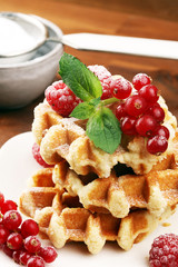 Traditional belgian waffles with fresh mint, sugar and raspberries on table