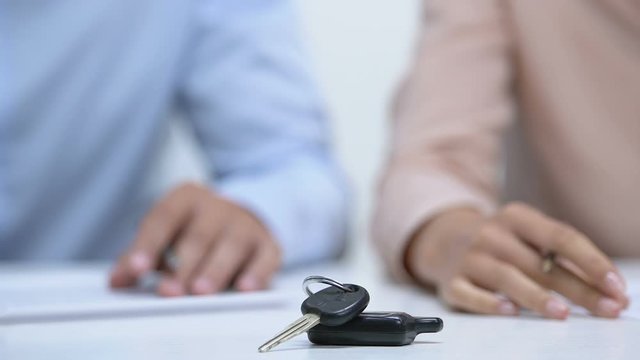 Family signing divorce documents, car key on table, division of property concept