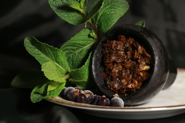 bowl with tobacco for hookah. berries on a black background