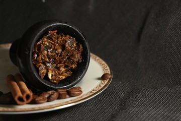bowl with tobacco for hookah. fruits on a black background. smoke hookah