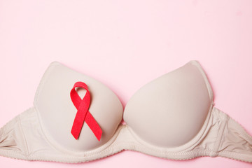 Bra with a symbol of the month of breast cancer awareness on a pink background top view, flat lay. Women's Health Concept.