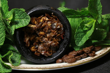 bowl with tobacco for hookah. fruits on a black background. smoking hookah