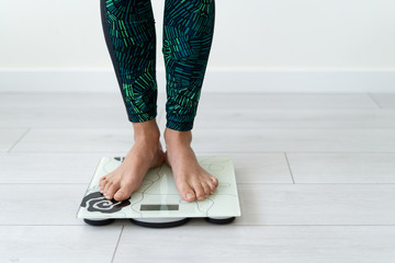 Young sporty woman standing on flooring scale weight