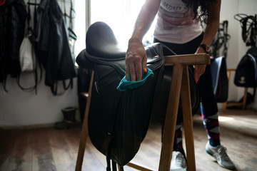 Cleaning and maintenance of the saddle. The woman rider cares for the saddle